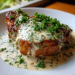 A beautifully seared pork chop smothered in creamy garlic sauce and topped with fresh parsley.