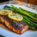 A perfectly cooked fillet of One-Pan Lemon Garlic Salmon with asparagus spears and lemon slices.