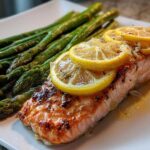 Close-up of a perfectly cooked One-Pan Lemon Garlic Salmon with asparagus spears, topped with lemon slices.