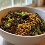 A close-up of One-Pot Beef and Broccoli Ramen Noodles mixed together in a white bowl.