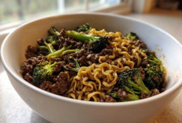 A close-up of One-Pot Beef and Broccoli Ramen Noodles mixed together in a white bowl.