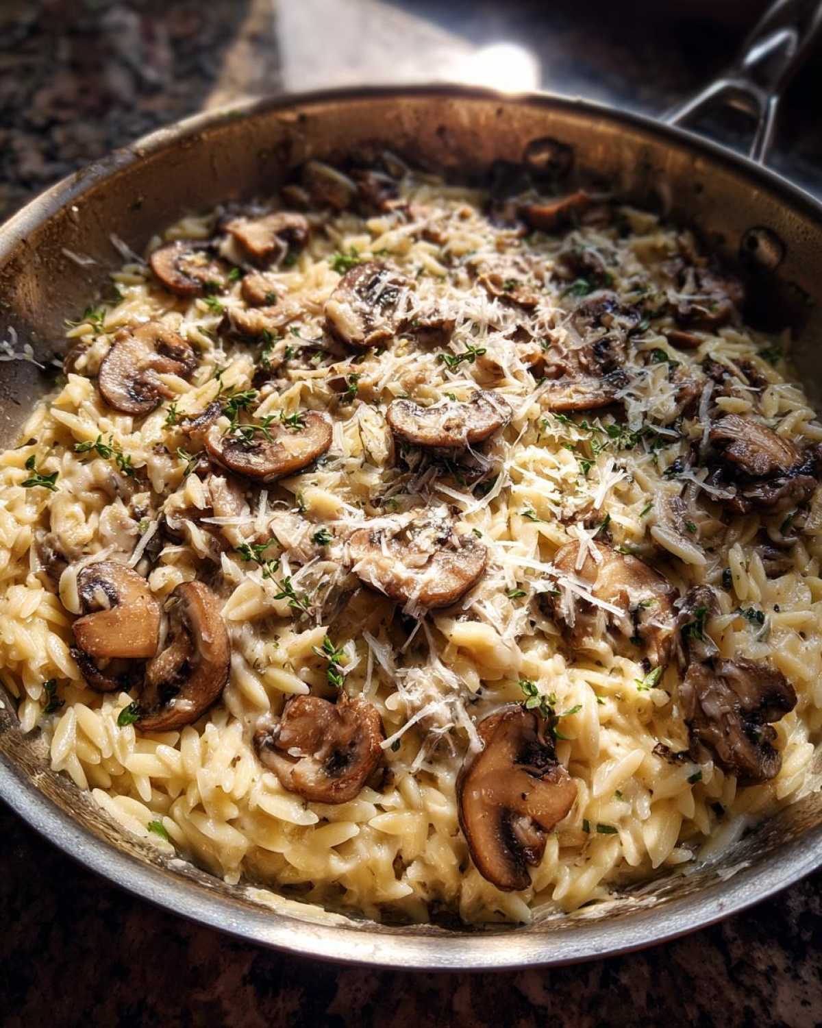 Close-up of One-Pot Creamy Mushroom Orzo topped with sliced mushrooms and grated cheese.