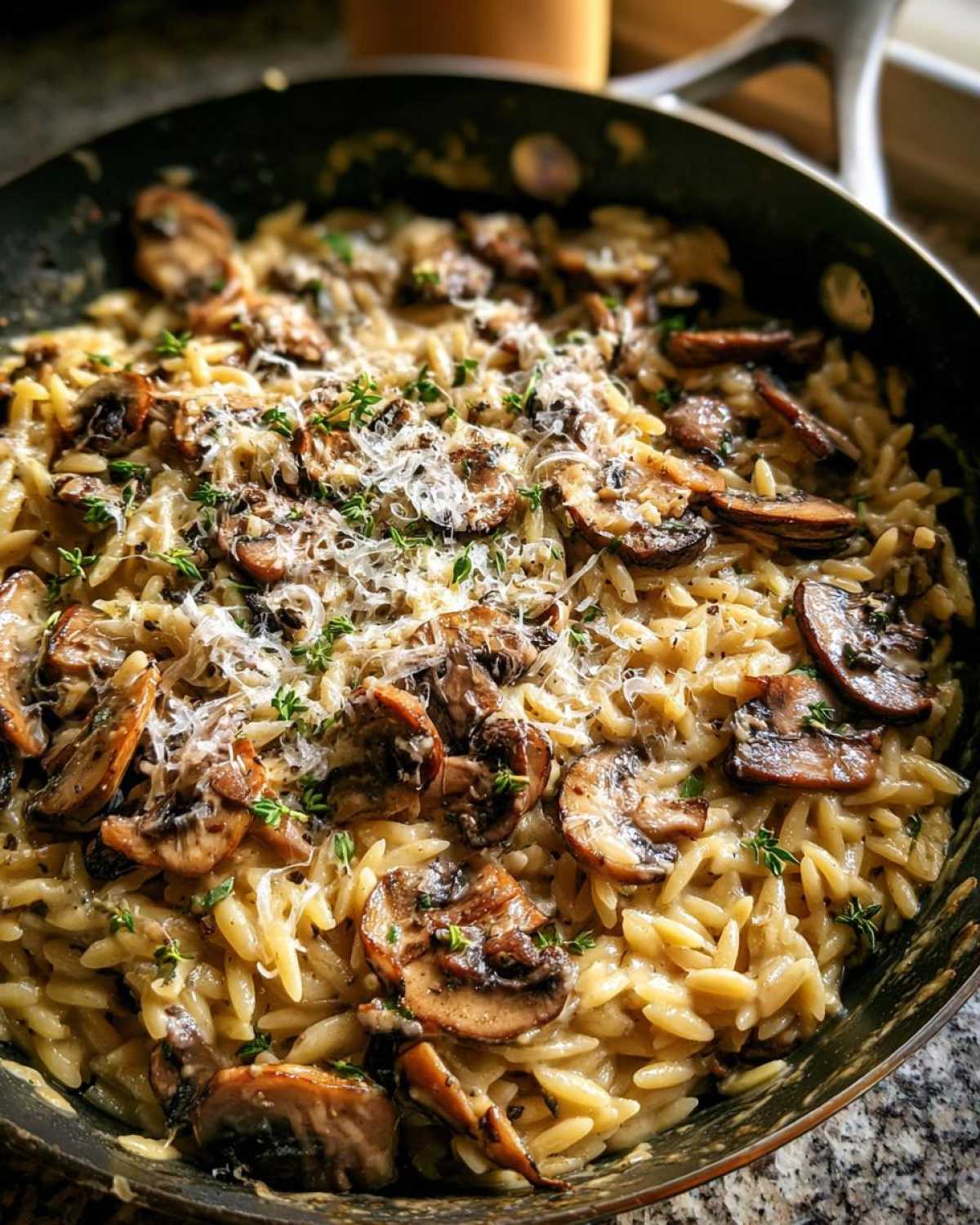 Close-up of One-Pot Creamy Mushroom Orzo topped with parmesan cheese and fresh thyme.