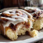 Close-up of two soft Gluten-Free Cinnamon Rolls drizzled with white icing on a white plate.