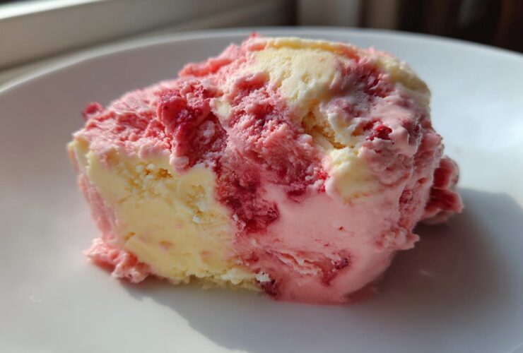 A close-up scoop of marbled Strawberry Banana Ice Cream showing swirls of pink strawberry and creamy yellow banana flavors.