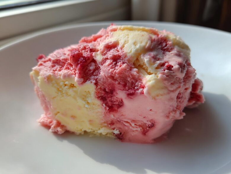 A close-up scoop of marbled Strawberry Banana Ice Cream showing swirls of pink strawberry and creamy yellow banana flavors.