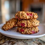 A stack of four delicious Strawberry Oatmeal Breakfast Cookies with visible oats and bright red strawberry pieces.