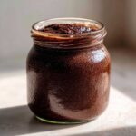 A close-up of rich, dark Vegan Chocolate Chia Pudding set inside a clear glass jar.