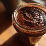 Overhead close-up of thick, dark Vegan Chocolate Chia Pudding texture in a glass jar.