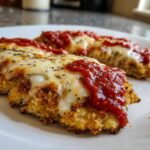 Two pieces of crispy Air Fryer Chicken Parmesan topped with melted mozzarella cheese and marinara sauce.