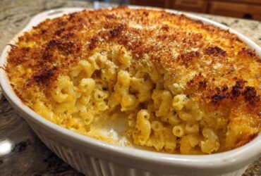 Close-up of Cheesy Baked Mac and Cheese with a golden, crispy breadcrumb top, served in a white oval baking dish.