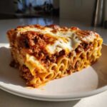 A perfect square slice of Cheesy Baked Ziti with Ground Beef and Sauce showing layers of ziti pasta, meat sauce, and melted cheese.