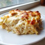 A generous serving of Cheesy Chicken Alfredo Bake with Mozzarella, featuring a golden-brown, bubbly cheese crust.