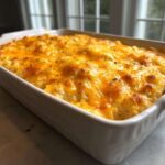 A close-up of a freshly baked Cheesy Chicken and Rice Casserole Easy Bake topped with melted, golden cheddar cheese.
