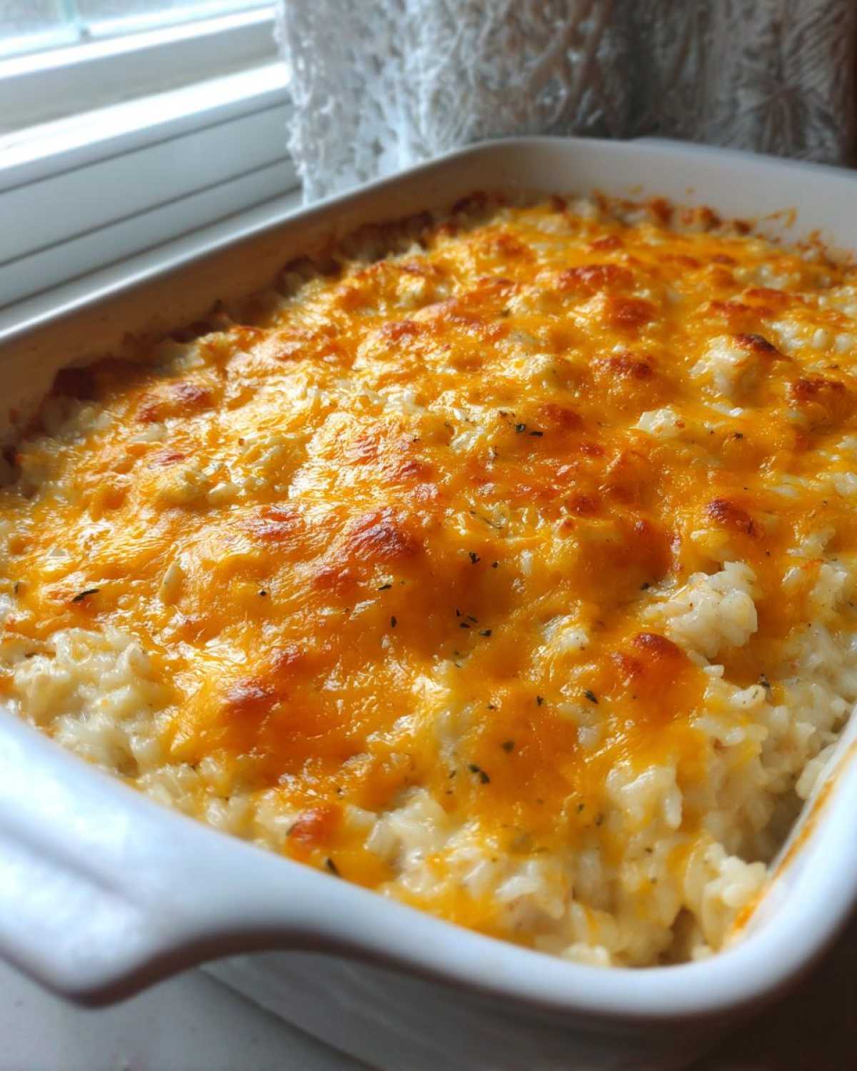 Close-up of a freshly baked Cheesy Chicken and Rice Casserole Easy Bake with melted, golden cheddar cheese topping.