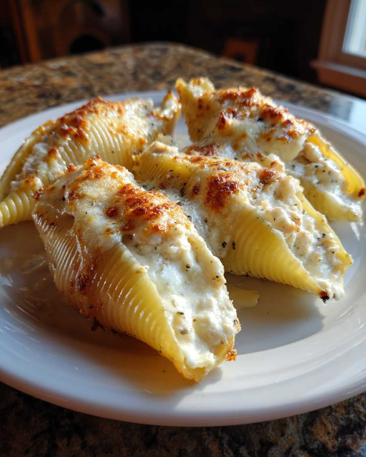 Four baked jumbo shells filled with Cheesy Chicken Stuffed Pasta mixture and topped with browned cheese.