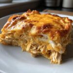 A close-up serving of Cheesy Chicken Tortilla Bake showing shredded chicken layers and a bubbly, golden melted cheese topping.