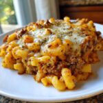 A close-up serving of Cheesy Ground Beef Pasta Bake with elbow macaroni, rich meat sauce, and a layer of melted, bubbly cheese topped with herbs.