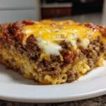 Close-up of a hearty slice of Cheesy Ground Beef Pasta Bake with melted cheddar and mozzarella cheese topping.