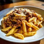 A close-up of penne pasta coated in a creamy sauce, topped with ground beef and grated cheese, showcasing the Cheesy Ground Beef Pasta.
