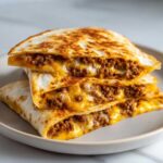 Three stacked, golden-brown wedges of Cheesy Ground Beef Quesadilla Easy Recipe, oozing with melted cheese and seasoned ground beef.