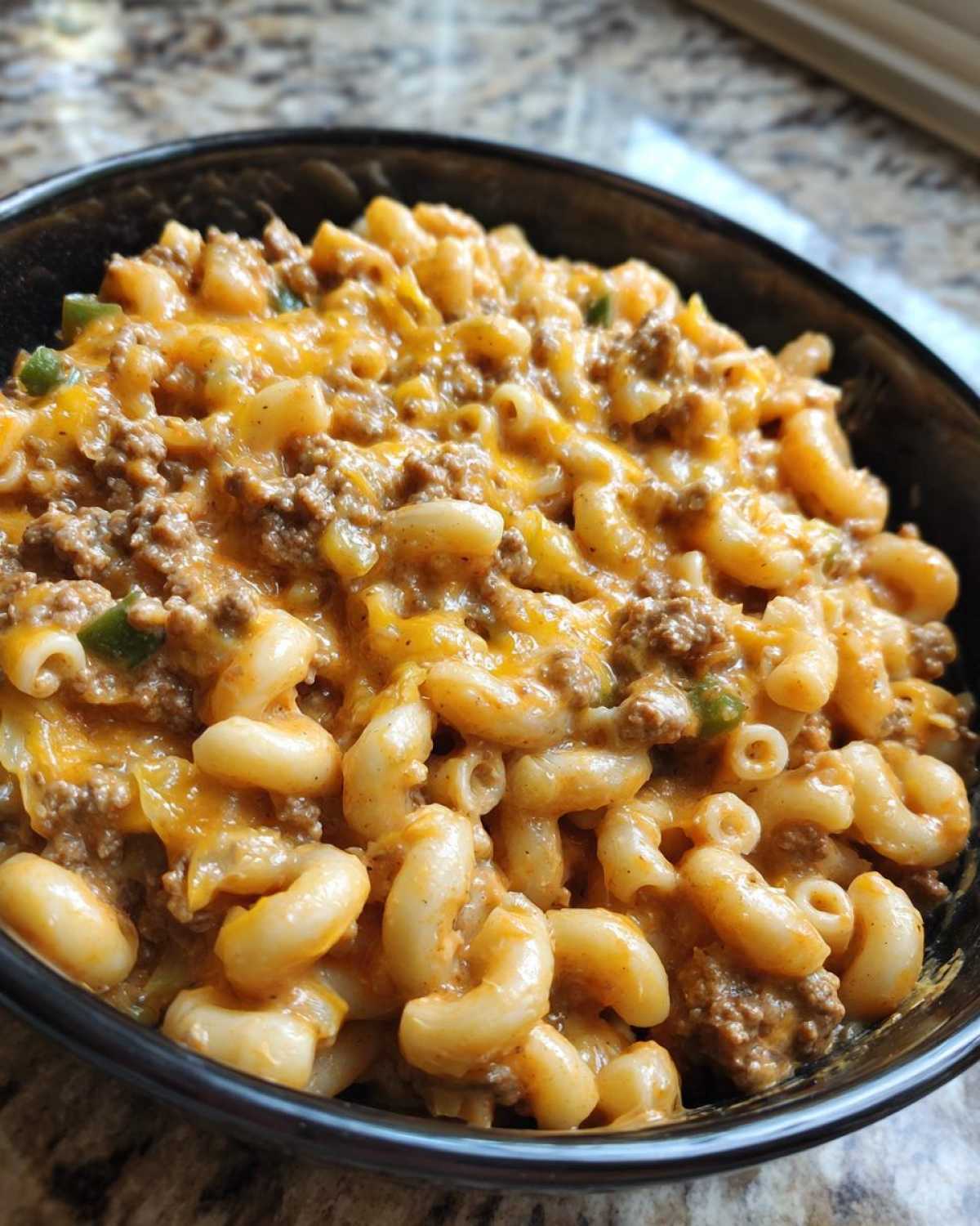 A close-up shot of a bowl filled with Cheesy Taco Pasta One Pot Dinner Idea, featuring elbow macaroni, seasoned ground beef, and melted cheddar cheese.