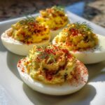 Four halves of Classic Deviled Eggs with Dill Pickle Relish, topped with paprika and fresh dill.