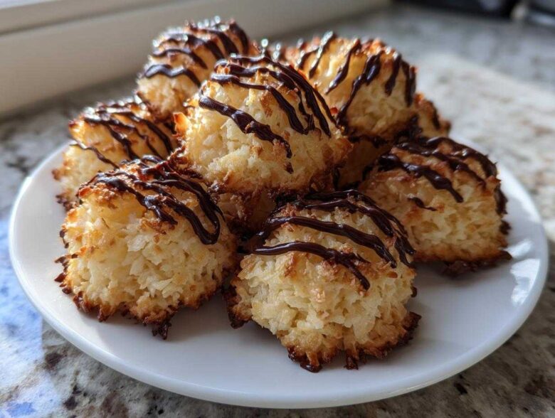 A stack of golden Coconut Macaroons with Dark Chocolate Drizzle served on a white plate.