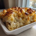 A close-up serving of Creamy Alfredo Chicken Bake in a white dish, showing creamy sauce and browned cheese topping.