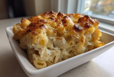 A close-up serving of Creamy Alfredo Chicken Bake in a white dish, showing creamy sauce and browned cheese topping.