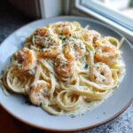 Close-up of a plate of Creamy Alfredo Shrimp Pasta with Garlic, topped with cooked shrimp and parsley.