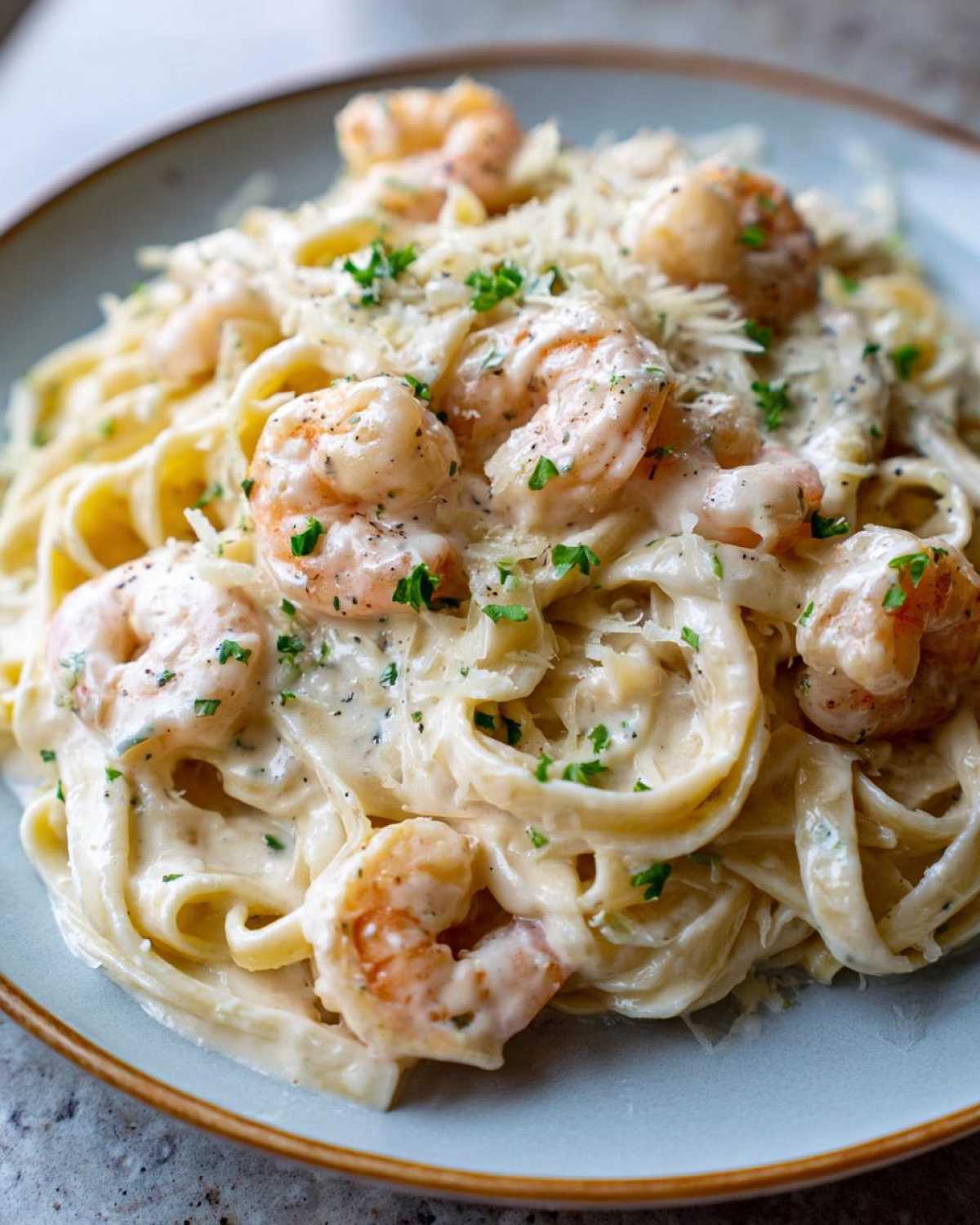 A close-up view of rich Creamy Alfredo Shrimp Pasta with Garlic, topped with grated Parmesan and fresh parsley.
