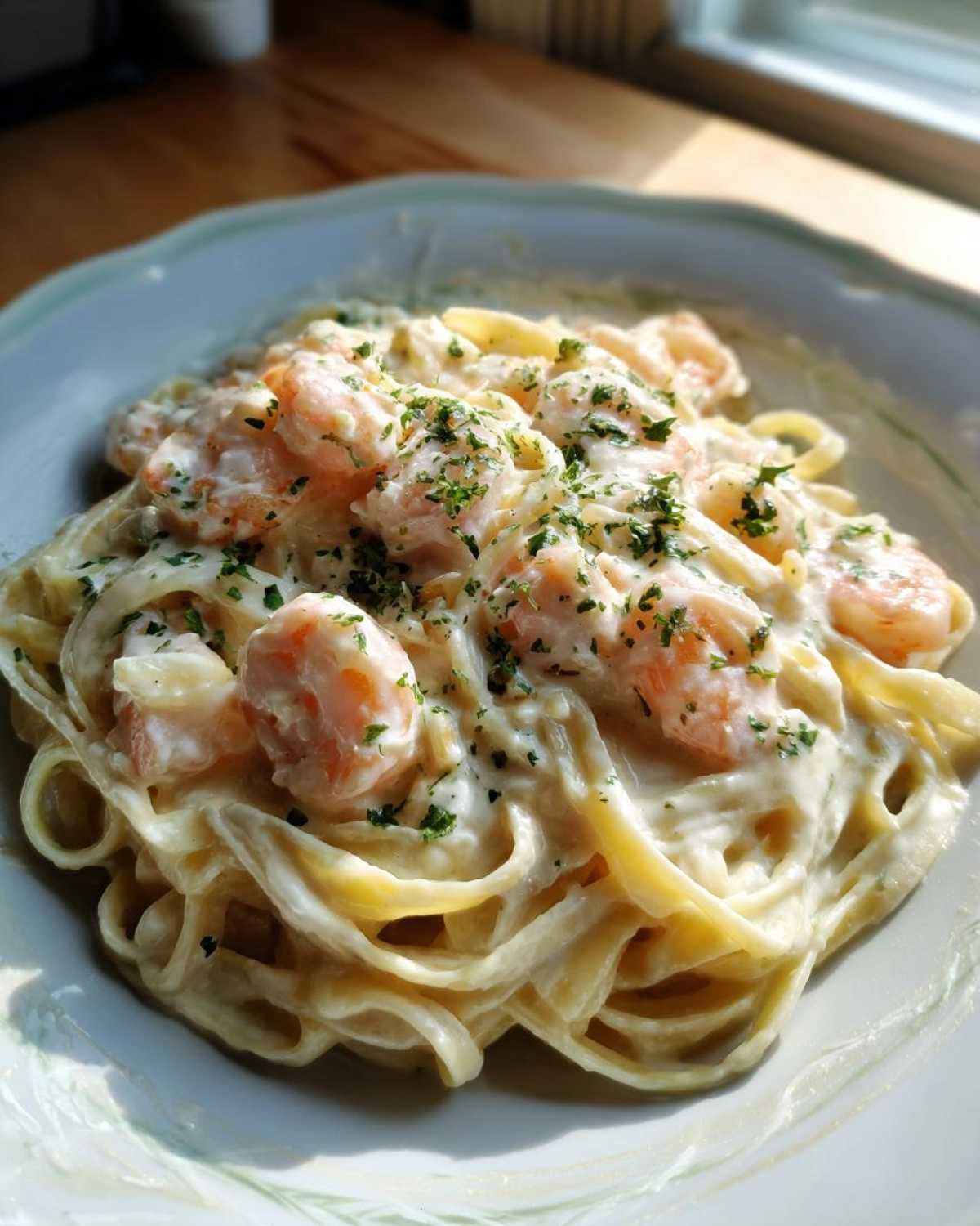 A close-up serving of rich Creamy Alfredo Shrimp Pasta with Garlic, topped with fresh parsley.