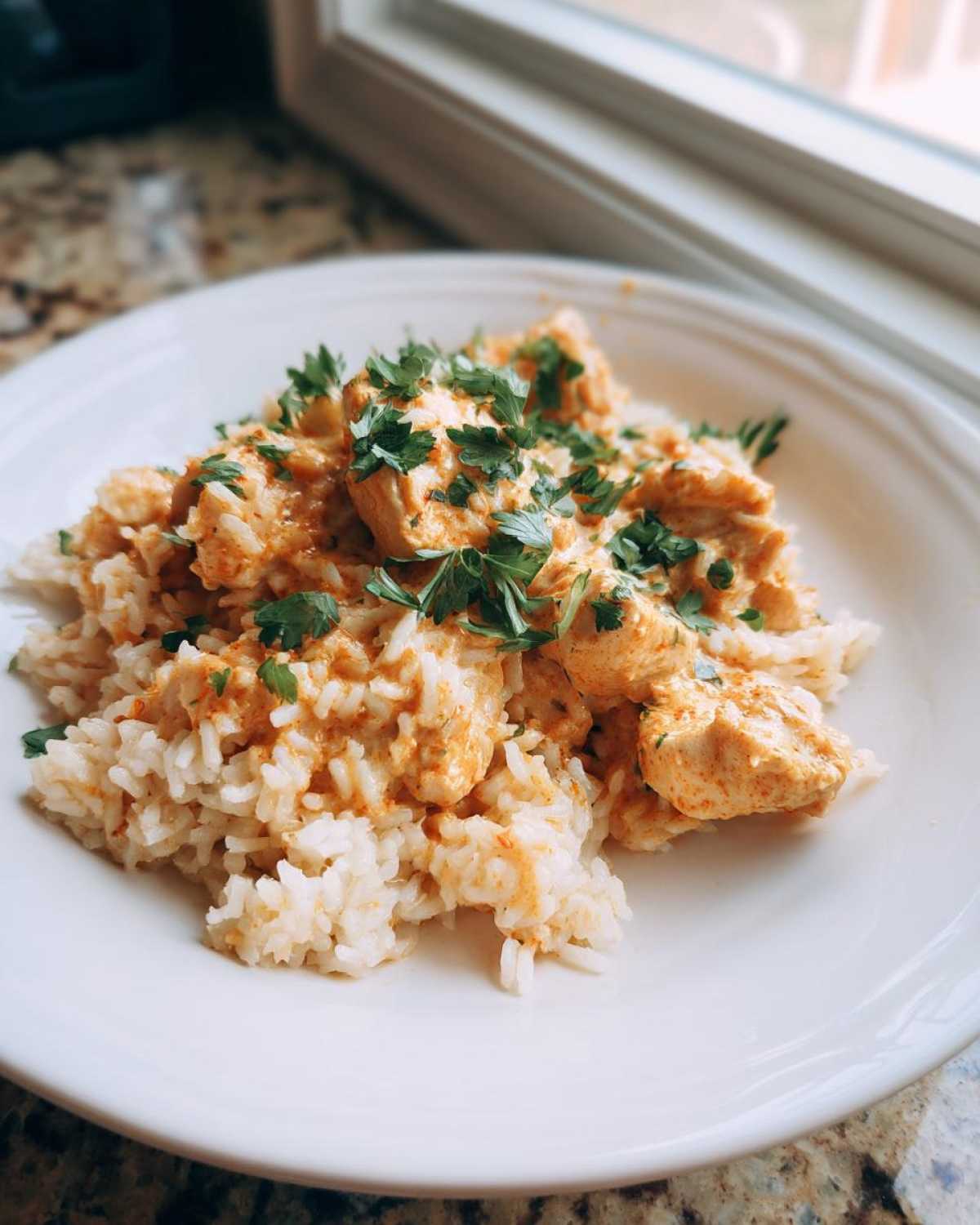 A plate of Creamy Cajun Chicken Rice One Pot Meal topped with fresh parsley garnish.