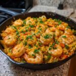 A close-up of a cast iron skillet filled with Creamy Cajun Shrimp and Rice Skillet, topped with fresh parsley.