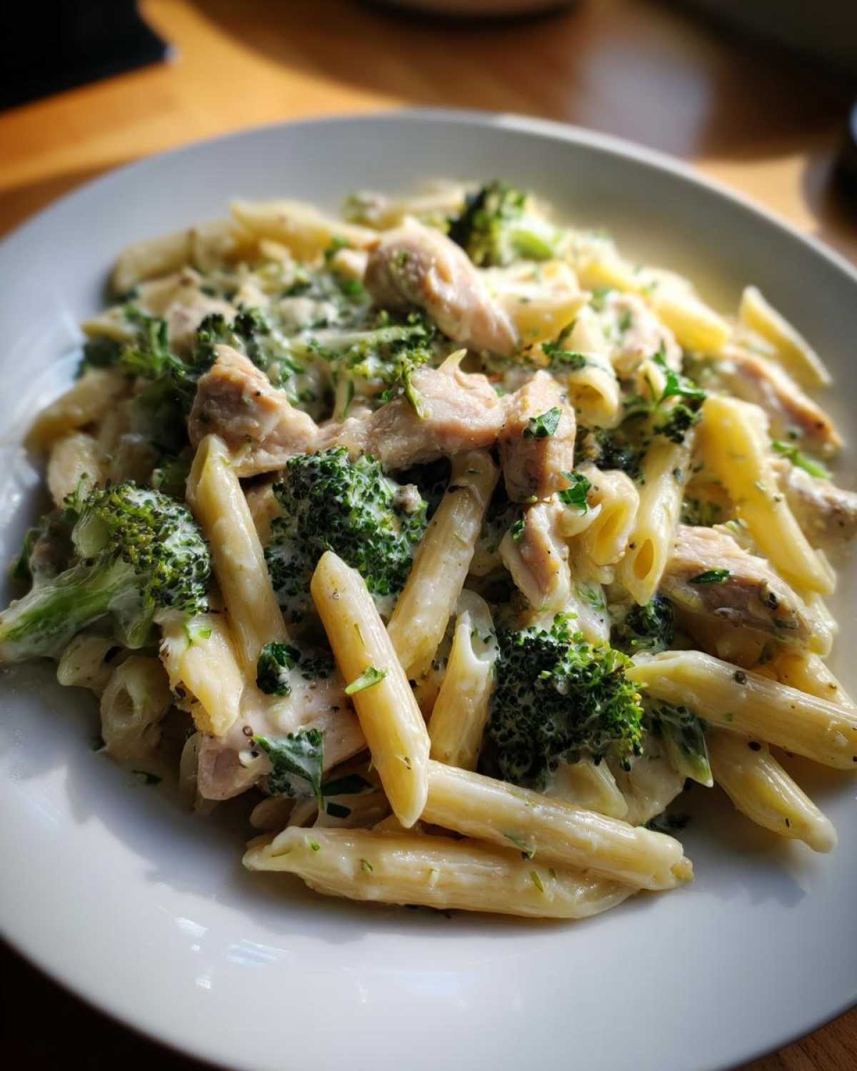 A close-up view of penne pasta tossed in a rich, creamy sauce with chunks of chicken and bright green broccoli florets, making a perfect Creamy Chicken and Broccoli Pasta Dinner.
