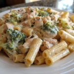 A close-up of a white plate filled with Creamy Chicken and Broccoli Pasta Dinner featuring penne pasta, chunks of chicken, and bright green broccoli florets.