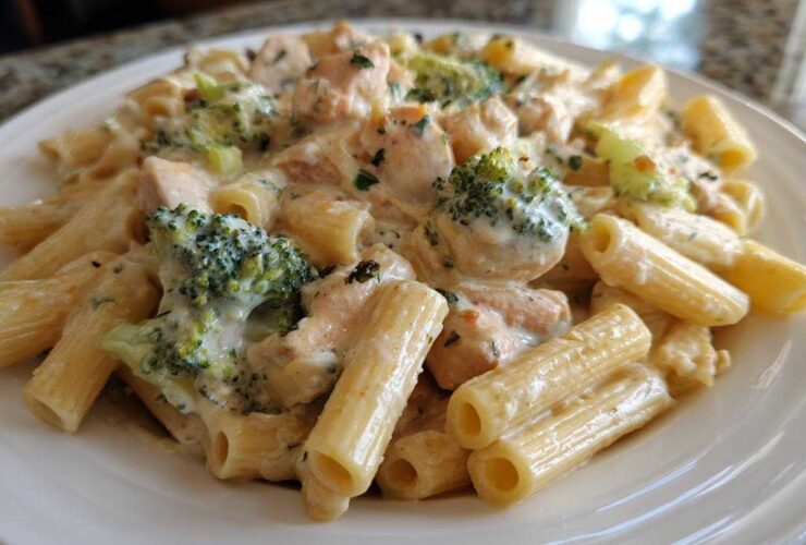 A close-up of a white plate filled with Creamy Chicken and Broccoli Pasta Dinner featuring penne pasta, chunks of chicken, and bright green broccoli florets.