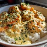 Close-up of a white bowl filled with white rice topped generously with creamy garlic shrimp and fresh parsley.
