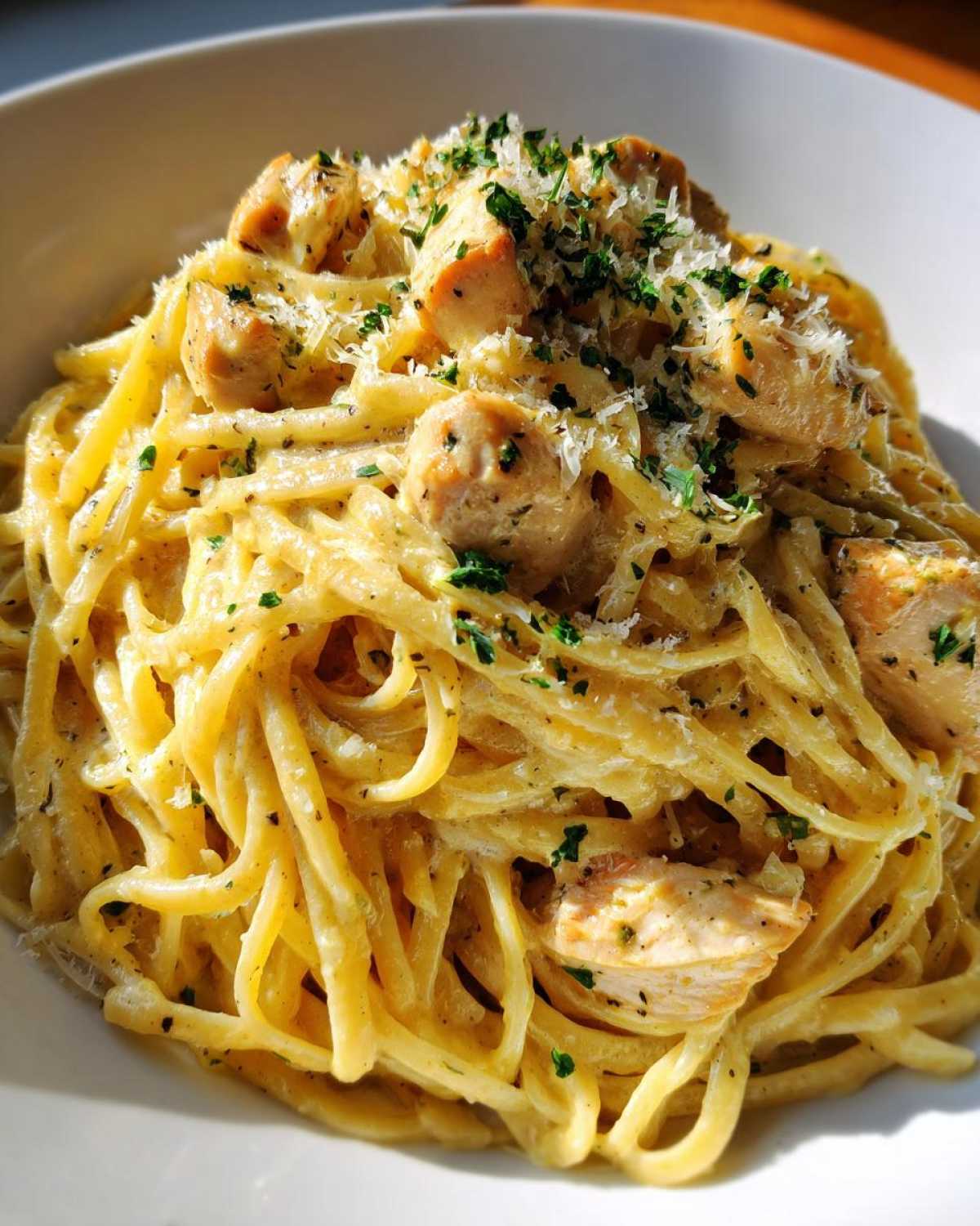 Close-up of Creamy Lemon Chicken Pasta with Parmesan, topped with herbs and cheese.