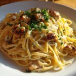A close-up of Creamy Lemon Garlic Pasta with Chicken, featuring fettuccine coated in a rich sauce and topped with seared chicken pieces and parsley.