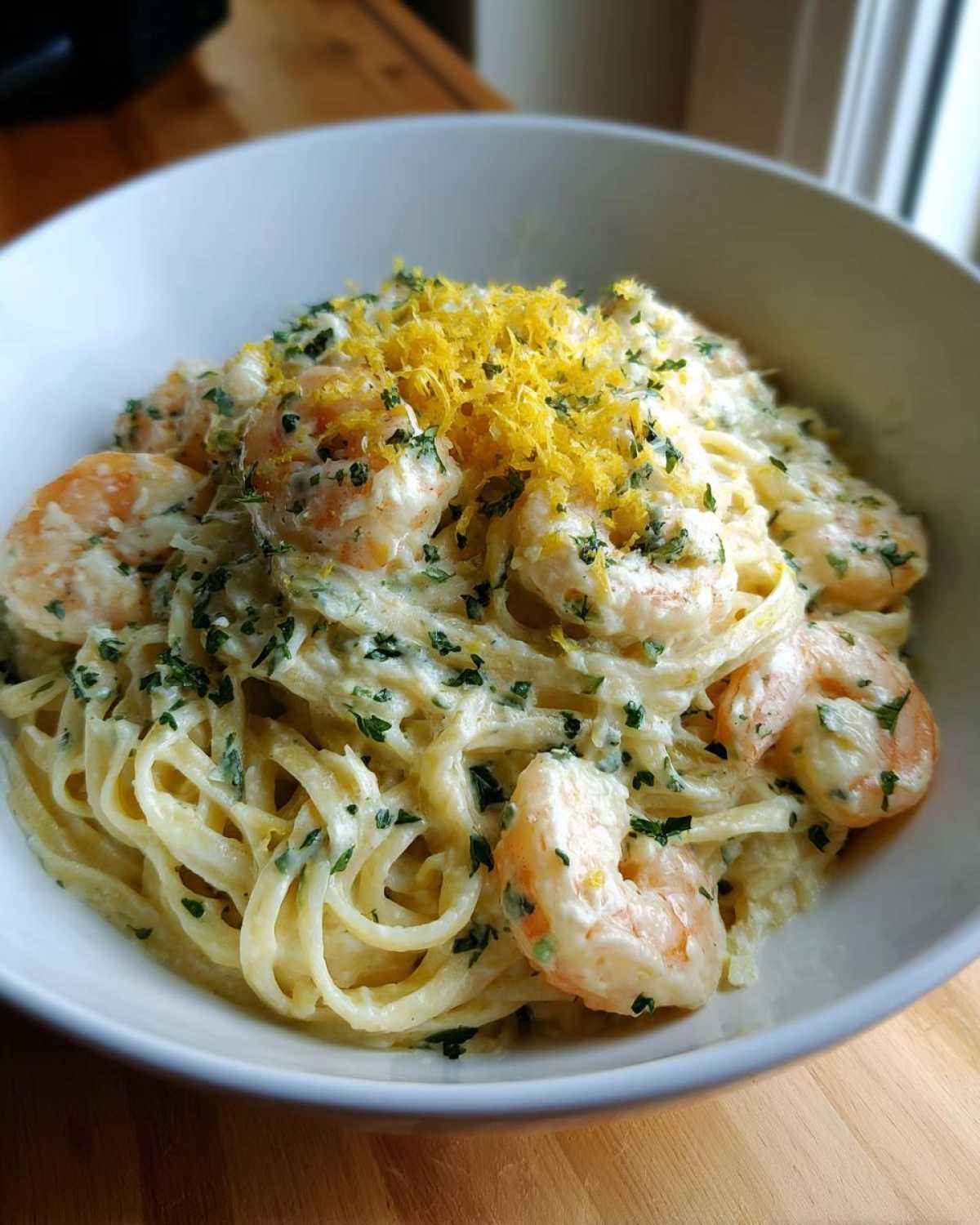 Close-up of Creamy Lemon Garlic Shrimp Pasta topped with bright yellow lemon zest and fresh parsley.