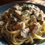 Close-up of a plate of Creamy Mushroom Chicken Pasta with fettuccine coated in a rich garlic sauce and topped with parsley.