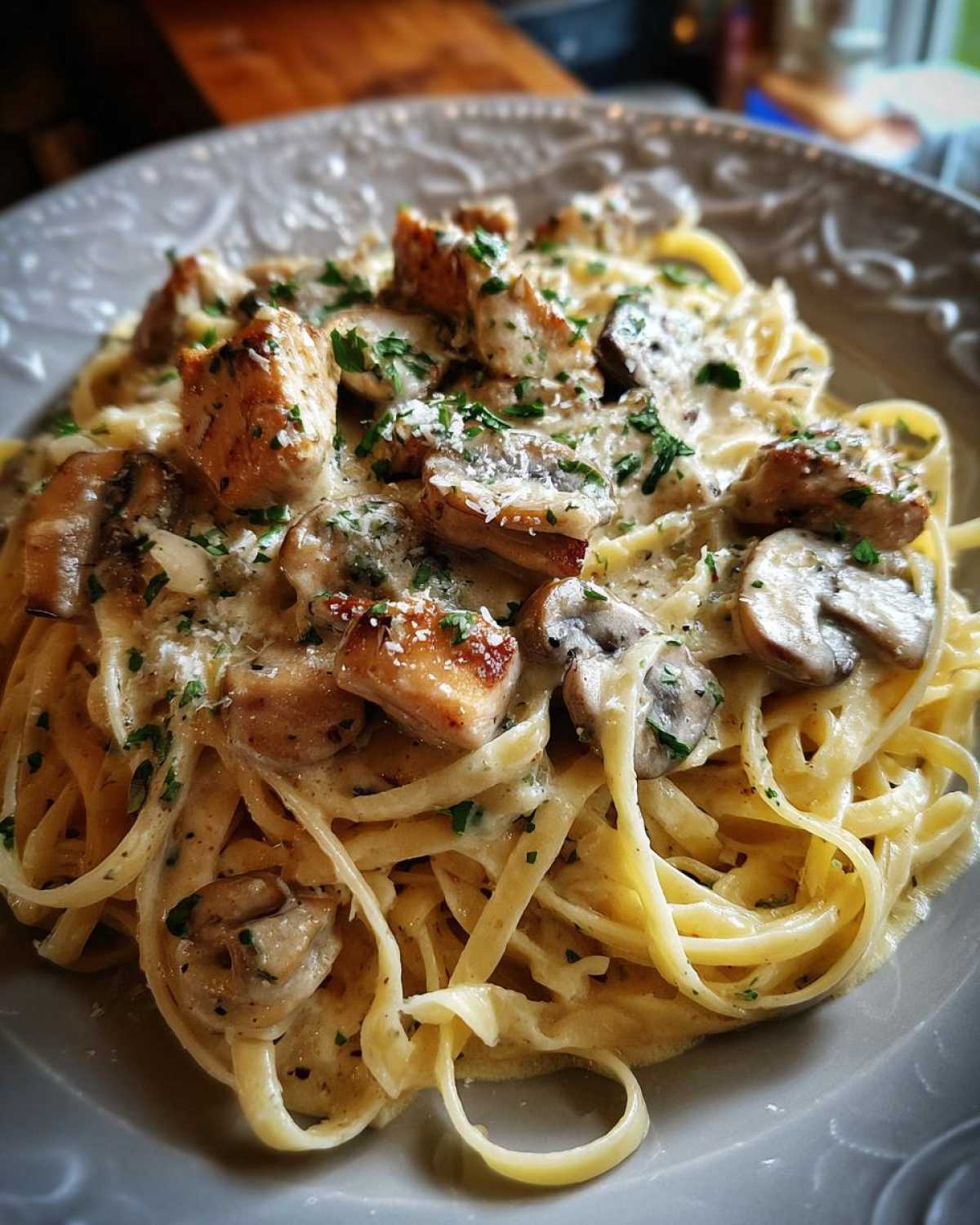 Close-up of Creamy Mushroom Chicken Pasta with fettuccine noodles coated in a rich garlic sauce, topped with chicken pieces and mushrooms.