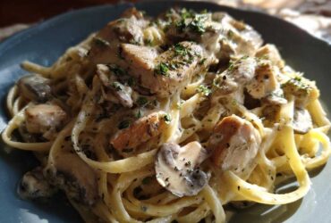Close-up of a plate of Creamy Mushroom Chicken Pasta with fettuccine coated in a rich garlic sauce and topped with parsley.