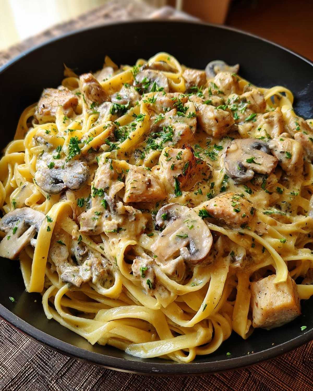 Close-up of Creamy Mushroom Chicken Pasta with fettuccine noodles, chunks of chicken, and sliced mushrooms in a rich garlic sauce.