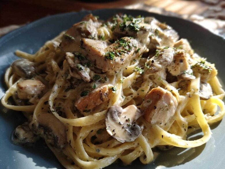 Close-up of a plate of Creamy Mushroom Chicken Pasta with fettuccine coated in a rich garlic sauce and topped with parsley.
