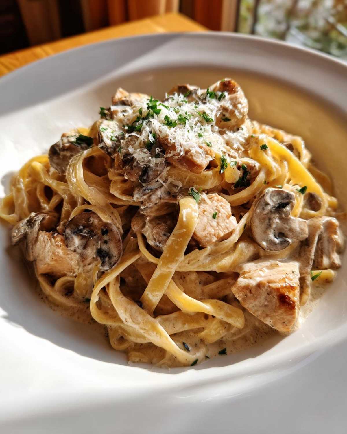 A close-up of Creamy Mushroom Chicken Pasta with Parmesan, featuring fettuccine, chicken pieces, mushrooms, and grated cheese.
