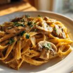 Close-up of fettuccine pasta coated in a rich, creamy mushroom sauce, garnished with fresh parsley.