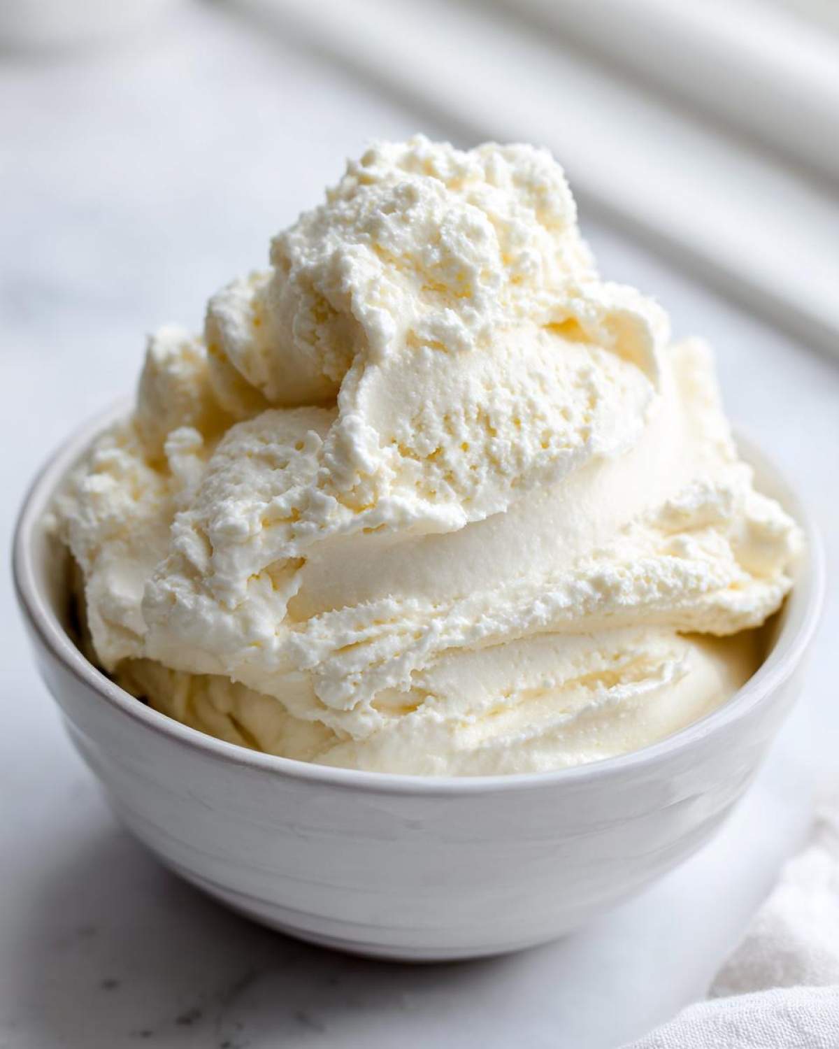 Close-up of a thick, creamy vanilla protein smoothie bowl base scooped into a white bowl.